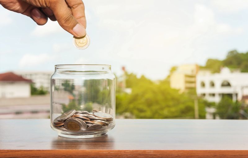 Image of a coin being dropped in a glass jar